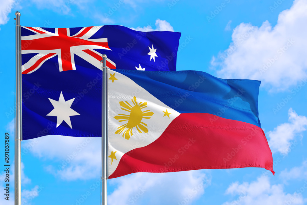 Philippines and Australia national flag waving in the windy deep blue sky. Diplomacy and international relations concept. Philippines and Australia national flag waving in the windy deep blue sky. Diplomacy and international relations concept.
