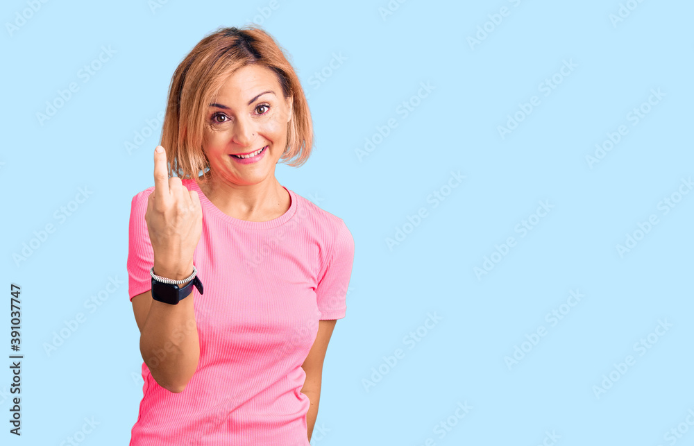 Young blonde woman wearing sportswear beckoning come here gesture with hand inviting welcoming happy and smiling Young blonde woman wearing sportswear beckoning come here gesture with hand inviting welcoming happy and smiling