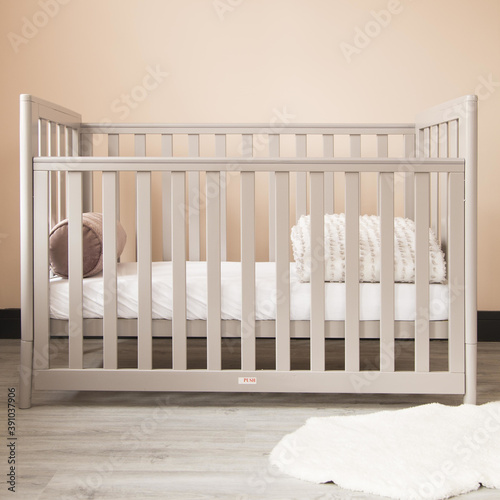 Modern baby room interior with a cozy classic crib and a soft neckroll pillow with blanket
