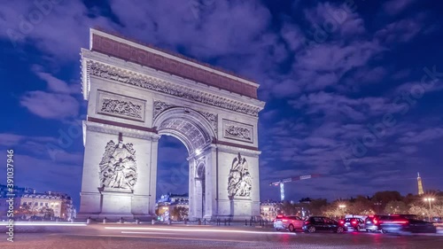 4K Timelapse of traffic at Arc de Triomph at night in an autumn winter day. This historical monument overlooks the avenue des champs élysées in the heart of Paris, French capital.  photo