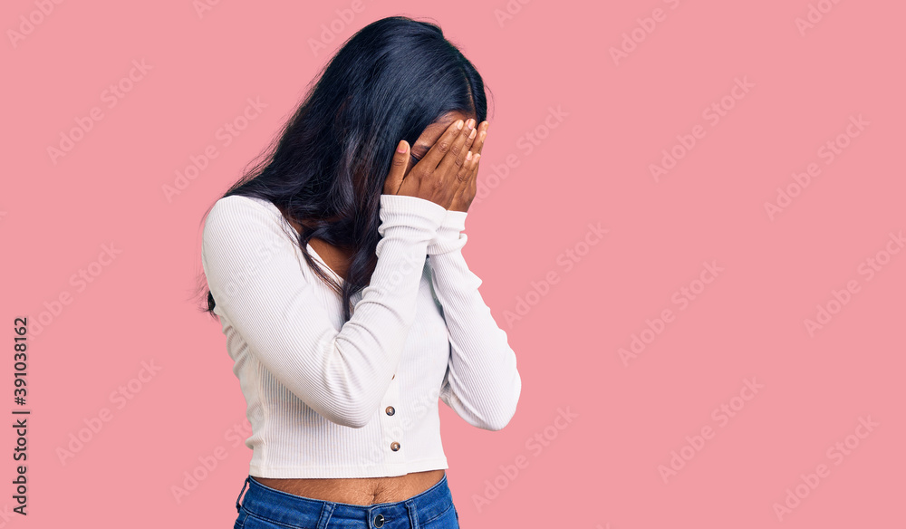 Young indian girl wearing casual clothes with sad expression covering face with hands while crying. depression concept.