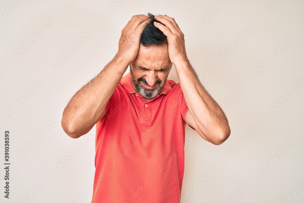 Middle age hispanic man wearing casual clothes suffering from headache desperate and stressed because pain and migraine. hands on head. Middle age hispanic man wearing casual clothes suffering from headache desperate and stressed because pain and migraine. hands on head.