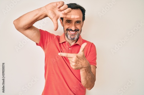 Middle age hispanic man wearing casual clothes smiling making frame with hands and fingers with happy face. creativity and photography concept.