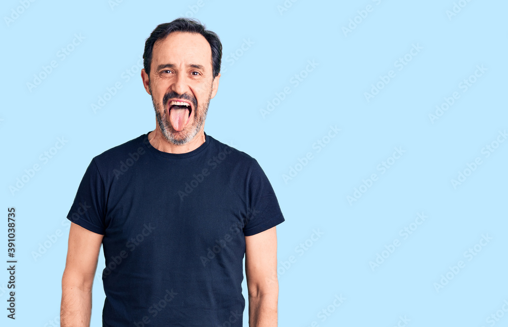 Middle age handsome man wearing casual t-shirt sticking tongue out happy with funny expression. emotion concept. Middle age handsome man wearing casual t-shirt sticking tongue out happy with funny expression. emotion concept.