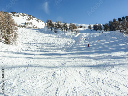 Some skiers on a snowy ski slope in the French Alps, in the resort of Risoul