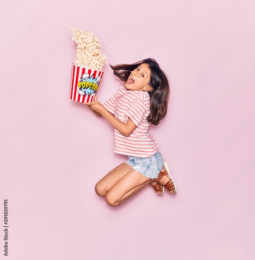 Φωτογραφία Adorable hispanic child girl surprised with open mouth holding bucket of popcorn