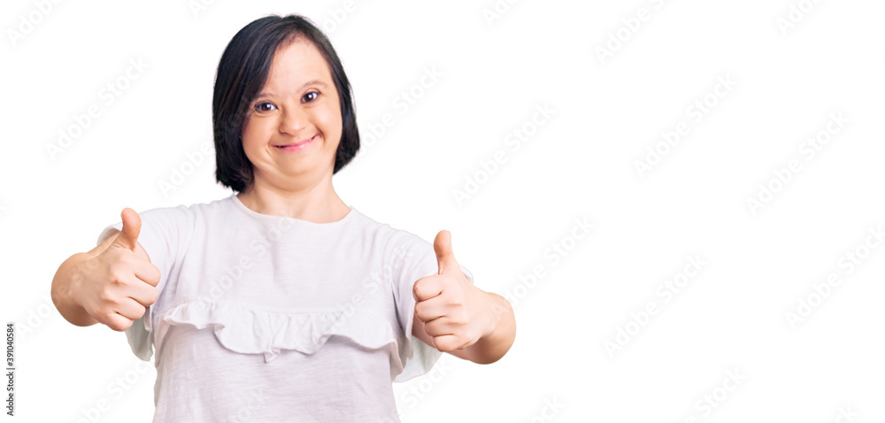 Brunette woman with down syndrome wearing casual white tshirt success sign doing positive gesture with hand, thumbs up smiling and happy. cheerful expression and winner gesture. Brunette woman with down syndrome wearing casual white tshirt success sign doing positive gesture with hand, thumbs up smiling and happy. cheerful expression and winner gesture.
