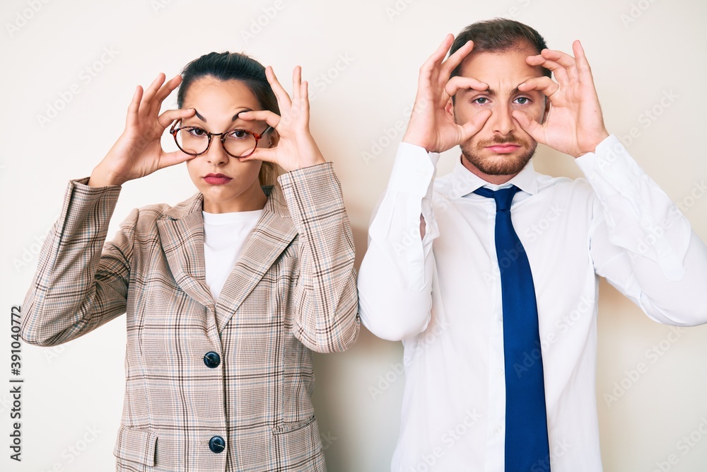 Beautiful couple wearing business clothes trying to open eyes with fingers, sleepy and tired for morning fatigue Beautiful couple wearing business clothes trying to open eyes with fingers, sleepy and tired for morning fatigue