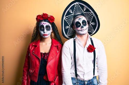 Couple wearing day of the dead costume over yellow depressed and worry for distress, crying angry and afraid. sad expression.