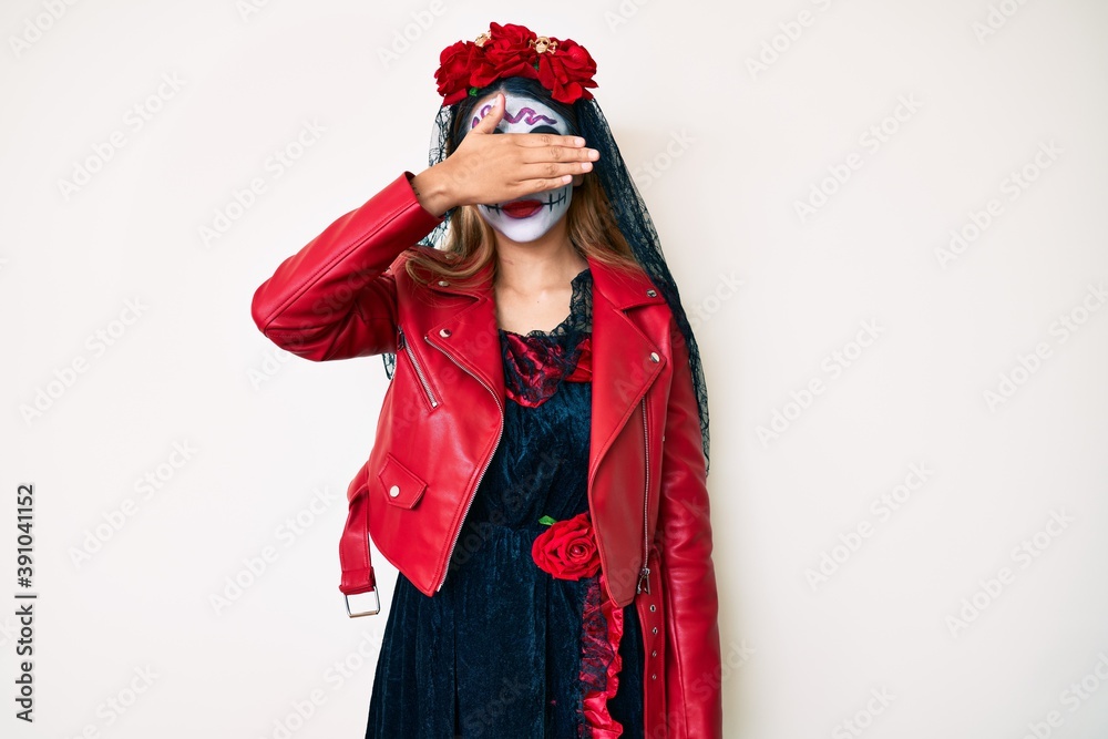 Woman wearing day of the dead costume over white covering eyes with hand, looking serious and sad. sightless, hiding and rejection concept