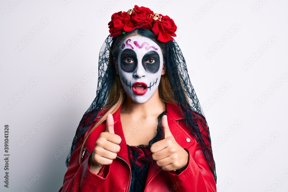 Woman wearing day of the dead costume with thumbs up doing ok sign in shock face, looking skeptical and sarcastic, surprised with open mouth