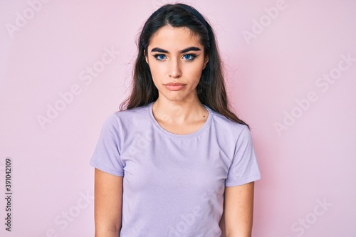 Brunette teenager girl wearing casual clothes with serious expression on face. simple and natural looking at the camera.