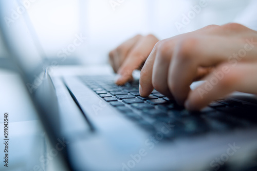 Close-up of male hands using laptop in office.