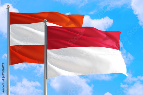 Indonesia and Austria national flag waving in the windy deep blue sky. Diplomacy and international relations concept.
