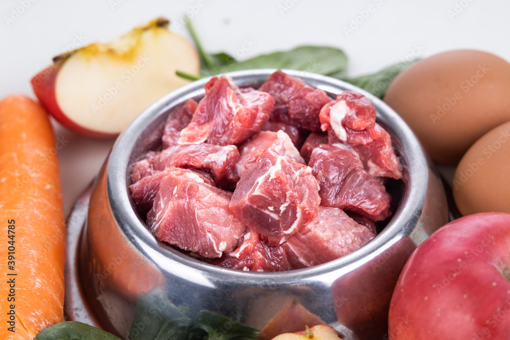 Closeup on barf raw meat chunk food for dog surrounded with other ingredients of vegetables and egg Closeup on barf raw meat chunk food for dog surrounded with other ingredients of vegetables and egg