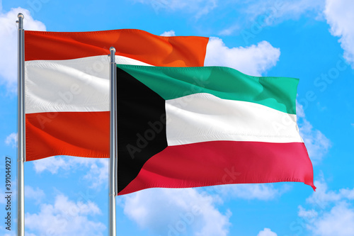 Kuwait and Austria national flag waving in the windy deep blue sky. Diplomacy and international relations concept.
