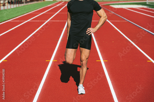 Fitness man stretching on the red running track. Front view. Close up. Lifestyle and sports