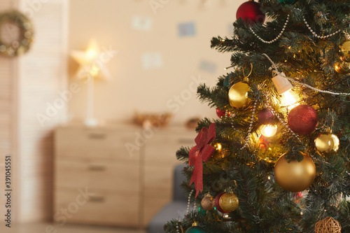 Background image of beautiful Christmas tree decorated with golden baulbs in cozy home interior, copy space photo