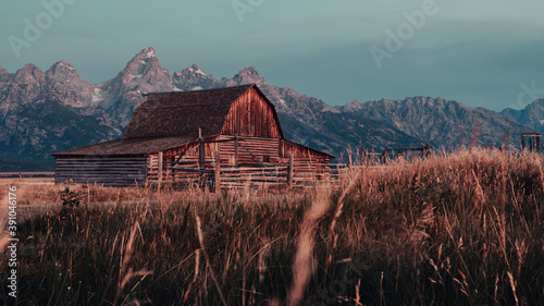 The Famous John Moulton Barn at sunrise in the Historic Mormon Row District of Grand Teton National Park, Wyoming, USA. Morning sunshine on the Teton Mountains in the background.  photo