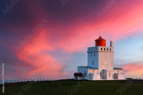 Amazing evening view of Dyrholaey Lighthouse at Cape Dyrholaey, south coast of Iceland. Great purple sunset glowing on background. Landscape photography