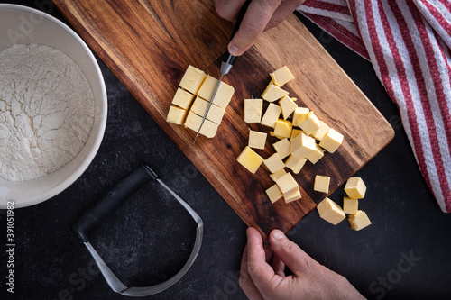 Photography Butter being cubed for pie dough, with bowl of flour, pastry knife and cutting b