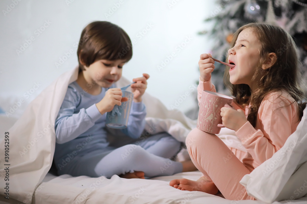 A family with children having fun on the bed under the covers during the Christmas holidays.