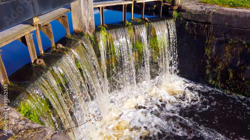 Water flowing over the wooden gates of a canal lock.