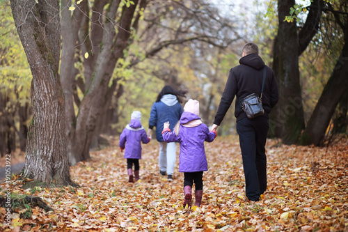 Young family on a walk in the autumn park on a sunny day. Happiness to be together. © alexkich