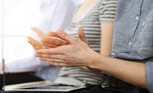 Business people clapping at meeting or conference, close-up of hands. Group of unknown businessmen and women in sunny office