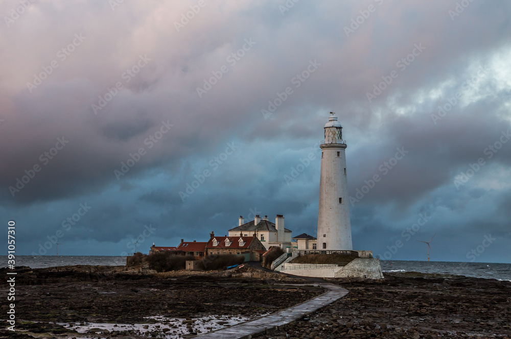 Big Clouds hang over St. Mary's Lighthouse in Whitley Bay at low tide, with the tidal causeway in view
