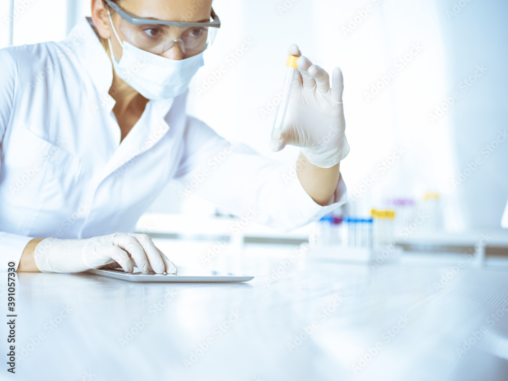 Female laboratory assistant analyzing a blood sample at hospital. Medicine, health care and researching concept Female laboratory assistant analyzing a blood sample at hospital. Medicine, health care and researching concept