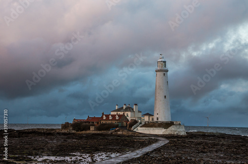 Big Clouds hang over St. Mary's Lighthouse in Whitley Bay at low tide, with the tidal causeway in view