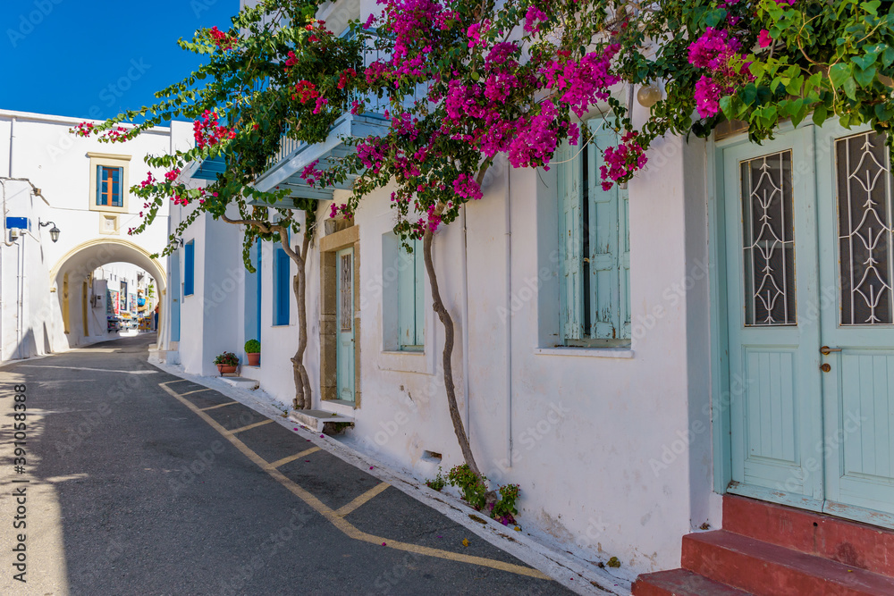 Traditional alley with narrow street, whitewashed houses and a blooming bougainvillea  in chora Kythira  island, Greece.