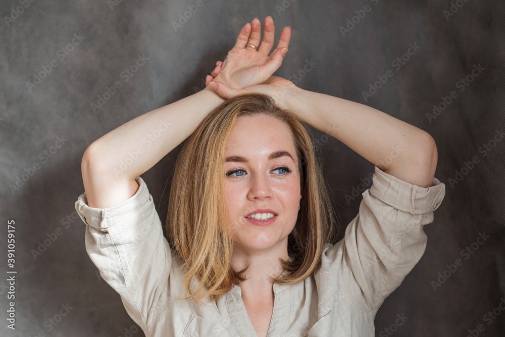 Smiling beautiful blonde European woman with hands near her head