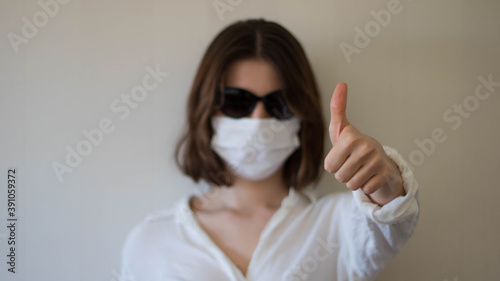 A business woman wearing sunglasses with mask making thumbs up, thumbs up sign with a face mask and sunglasses, face mask and thumbs up