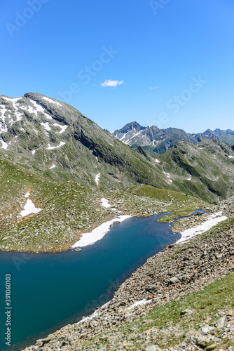 Fototapeta Naklejka Na Ścianę i Meble -  Wild lake Southtirol Italia Val pusteria Alpine pastures with a deep blue lake, green meadows and a blue sky with fleecy clouds, in summer