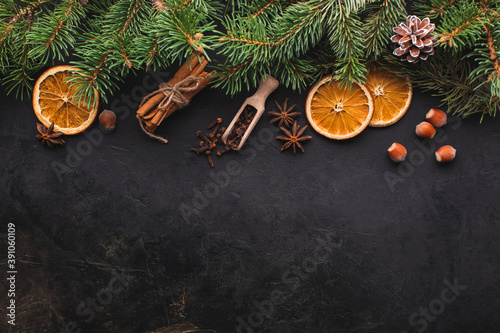 Christmas black background with fir branches, spices,oranges. View from above with copy space