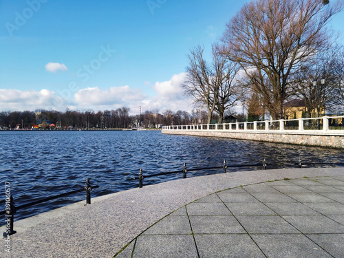 Low angle view from embankment of Upper Lake - artificial city pond, famous tourist attraction and popular leisure zone in Kaliningrad, Russia at sunny winter day photo