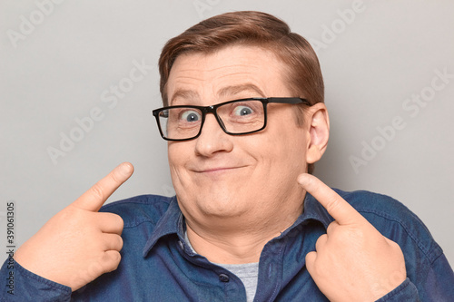Portrait of funny happy man pointing with fingers at himself