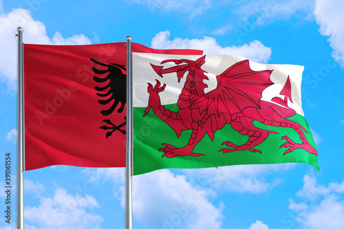 Wales and Albania national flag waving in the windy deep blue sky. Diplomacy and international relations concept.