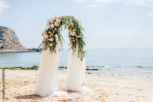Beautiful beach wedding venue setup at cabanas beach, decorated flower arch in Algarve Portugal