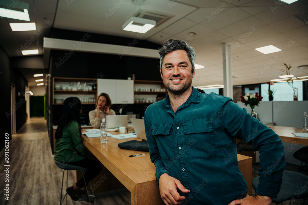 Portrait of smiling caucasian business man sitting against office table enjoying lunch break 