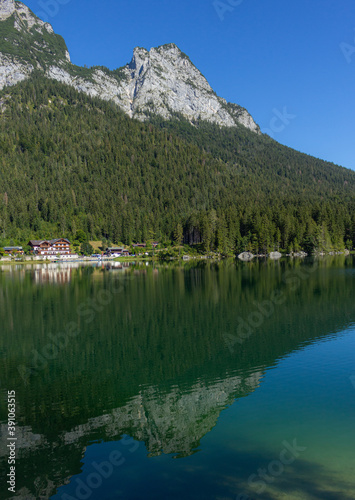Berchtesgaden lake Hintersee with trees in foreground and mountains in the background on a summer day