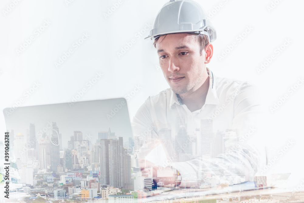 Double exposure of construction engineer wearing hard hat with laptop and view of city. Double exposure of construction engineer wearing hard hat with laptop and view of city.