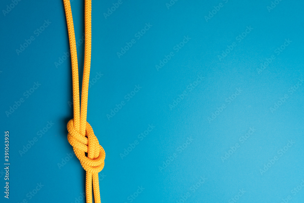 Figure-eight knot with climbing yellow rope on blue background