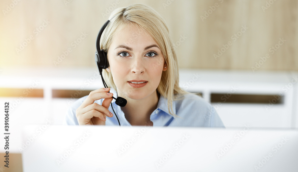 Blonde business woman sitting and communicated by headset in call center in sunny office. Concept of telesales business Blonde business woman sitting and communicated by headset in call center in sunny office. Concept of telesales business