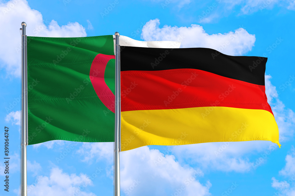 Obraz premium Germany and Algeria national flag waving in the windy deep blue sky. Diplomacy and international relations concept.