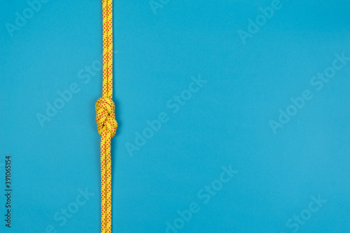 Figure-eight knot with climbing yellow rope on blue background