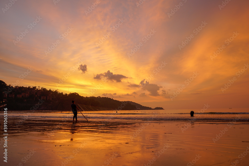.People come out to trawl their nets on Patong beach during sunset time..