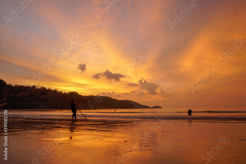 .People come out to trawl their nets on Patong beach during sunset time.. © Narong Niemhom